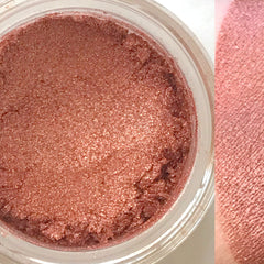 Vegan eyeshadow, shimmering rose-gold powder in a clear jar, swatch on skin