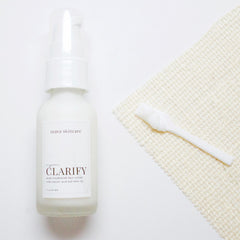 Face cream bottle with white pump, white label, and beige woven cloth beside it