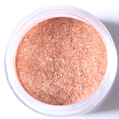 Glass jar of loose mineral eyeshadow in shimmering rose gold with metallic finish, lid removed