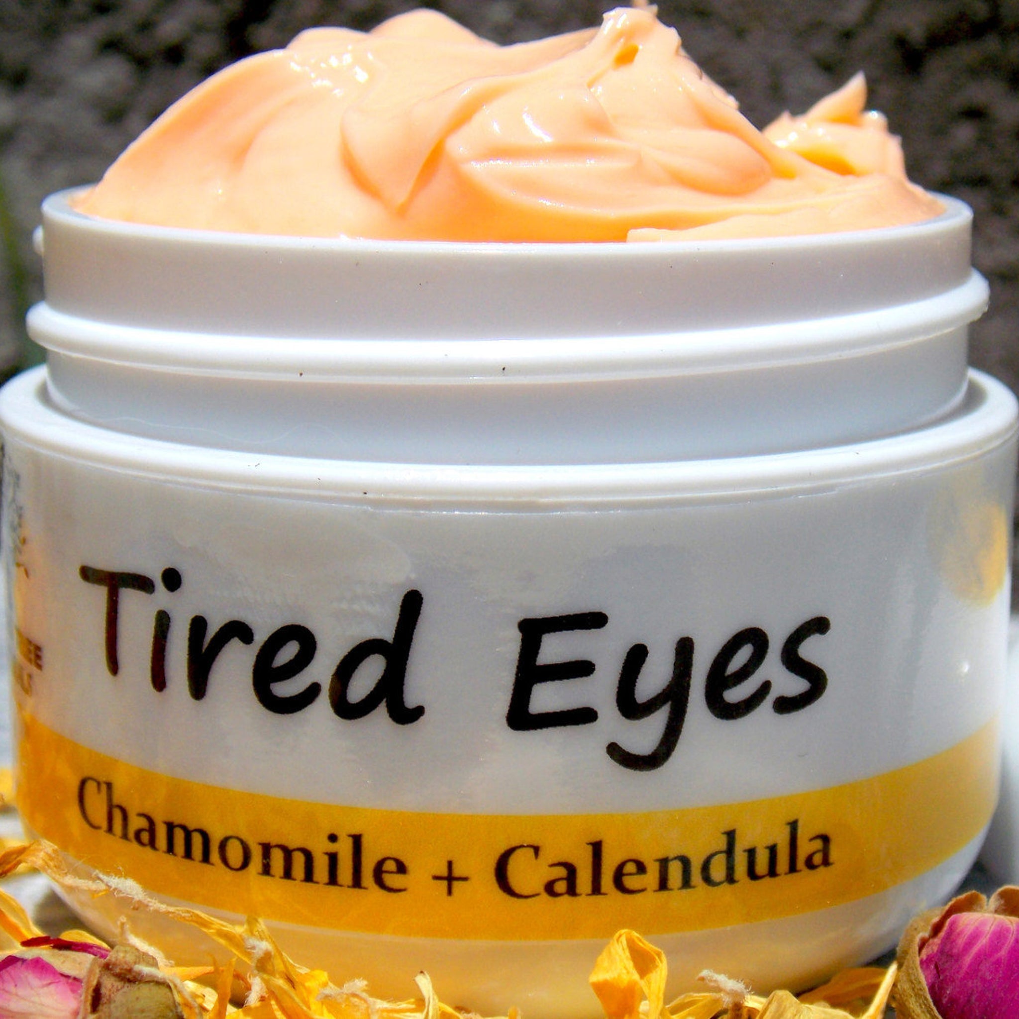 Tired Eyes cream in white jar with orange cream and text "Tired Eyes" and "Chamomile + Calendula