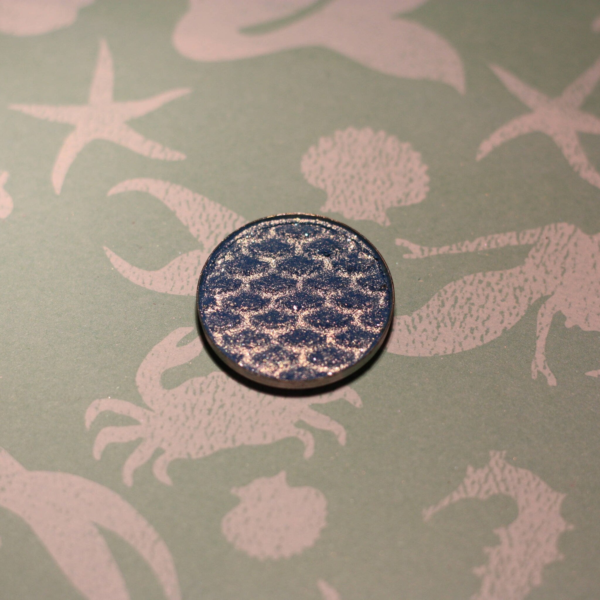 Close-up of Atlantis Eye Shadow in a vibrant teal shade with shimmer finish, displayed in a compact case.