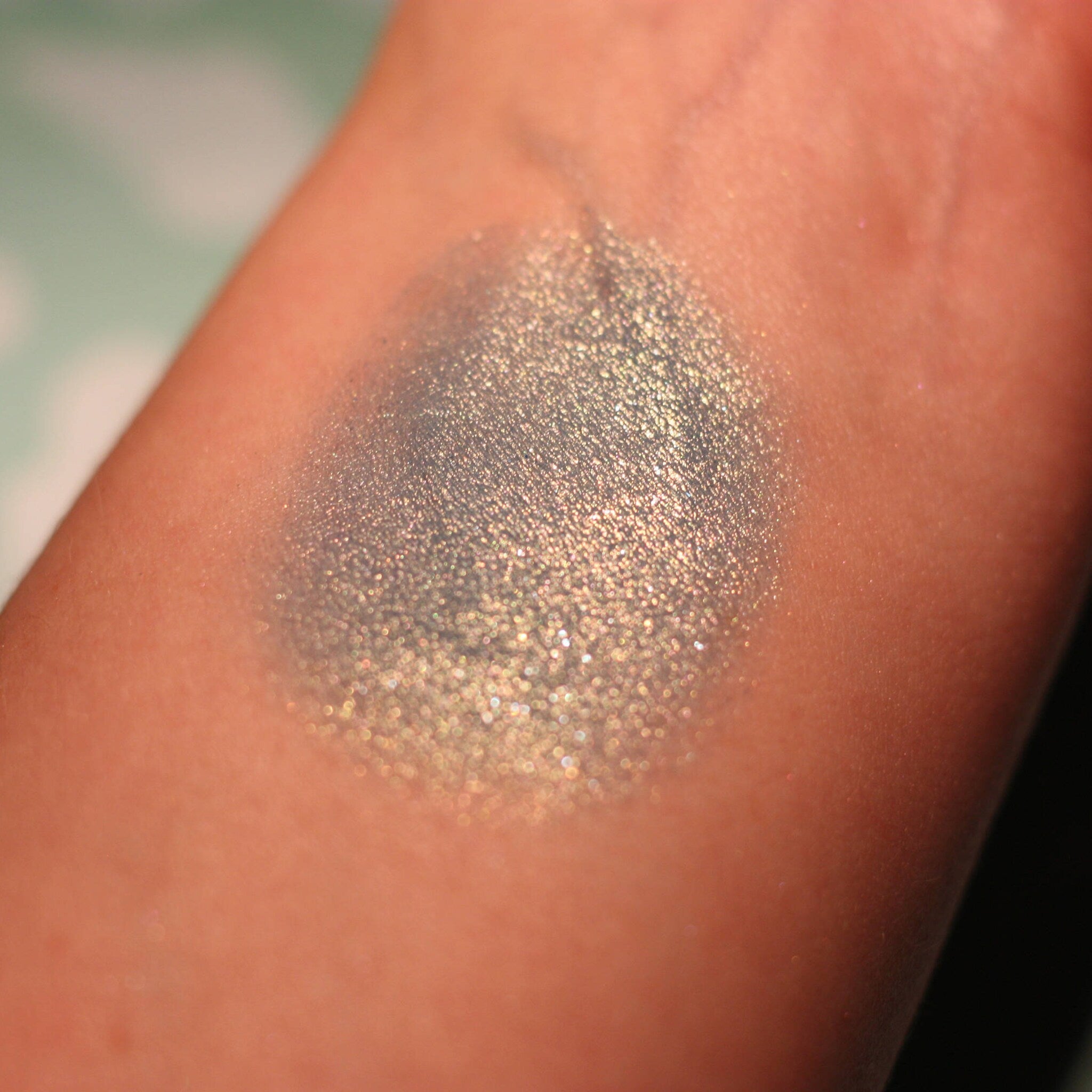 Side view of Atlantis Eye Shadow pot showcasing emerald green shimmer and compact circular packaging