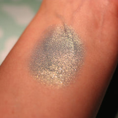 Side view of Atlantis Eye Shadow pot showcasing emerald green shimmer and compact circular packaging