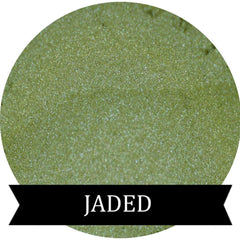 Close-up of jade green pressed powder eyeshadow in sleek black compact with gold lettering