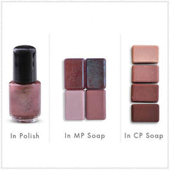 Nail polish bottle with black cap and pinkish-brown liquid next to soap bars in various shades of brown and pink