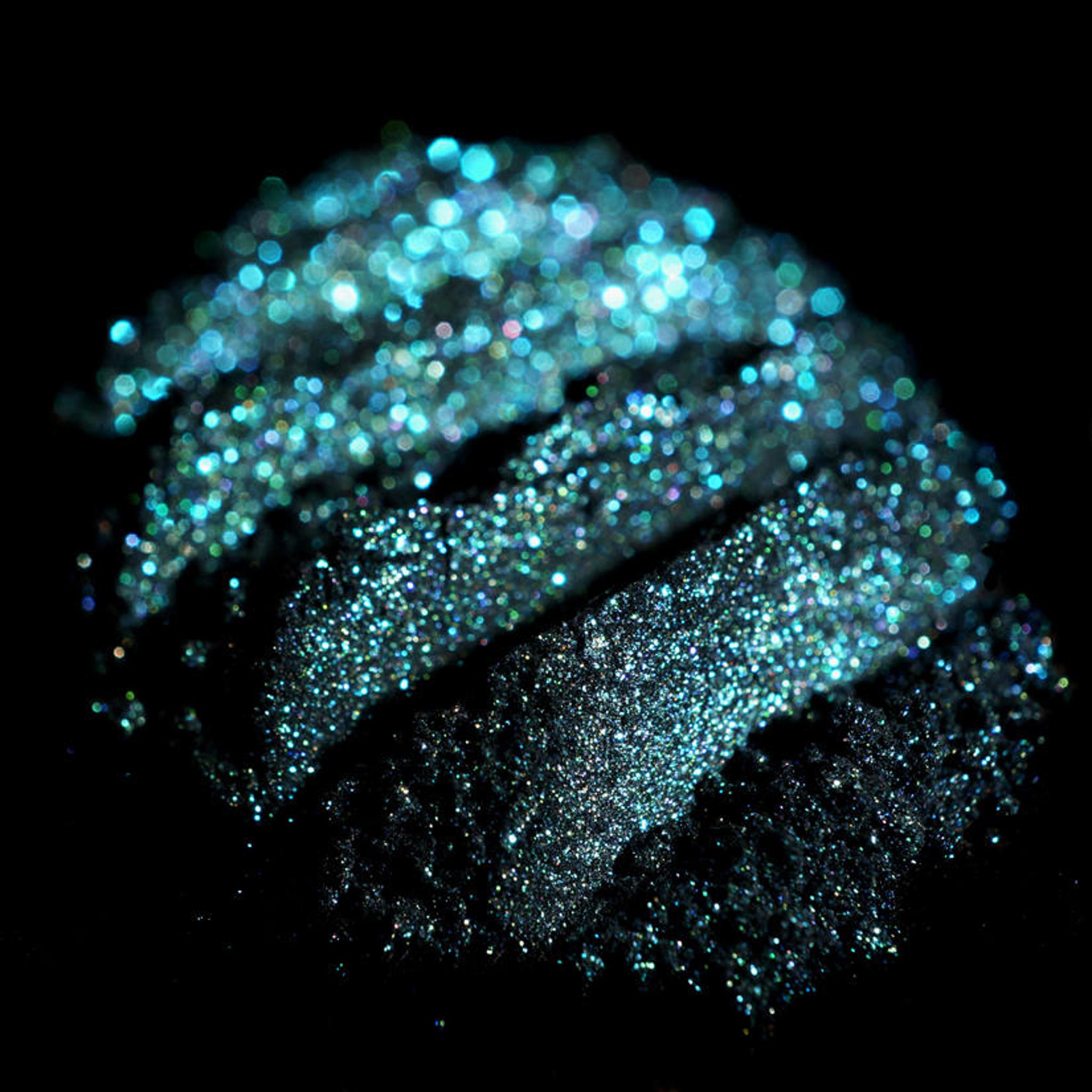 Open compact showcasing iridescent teal eyeshadow with colorshifting glitter in mermaid-inspired packaging