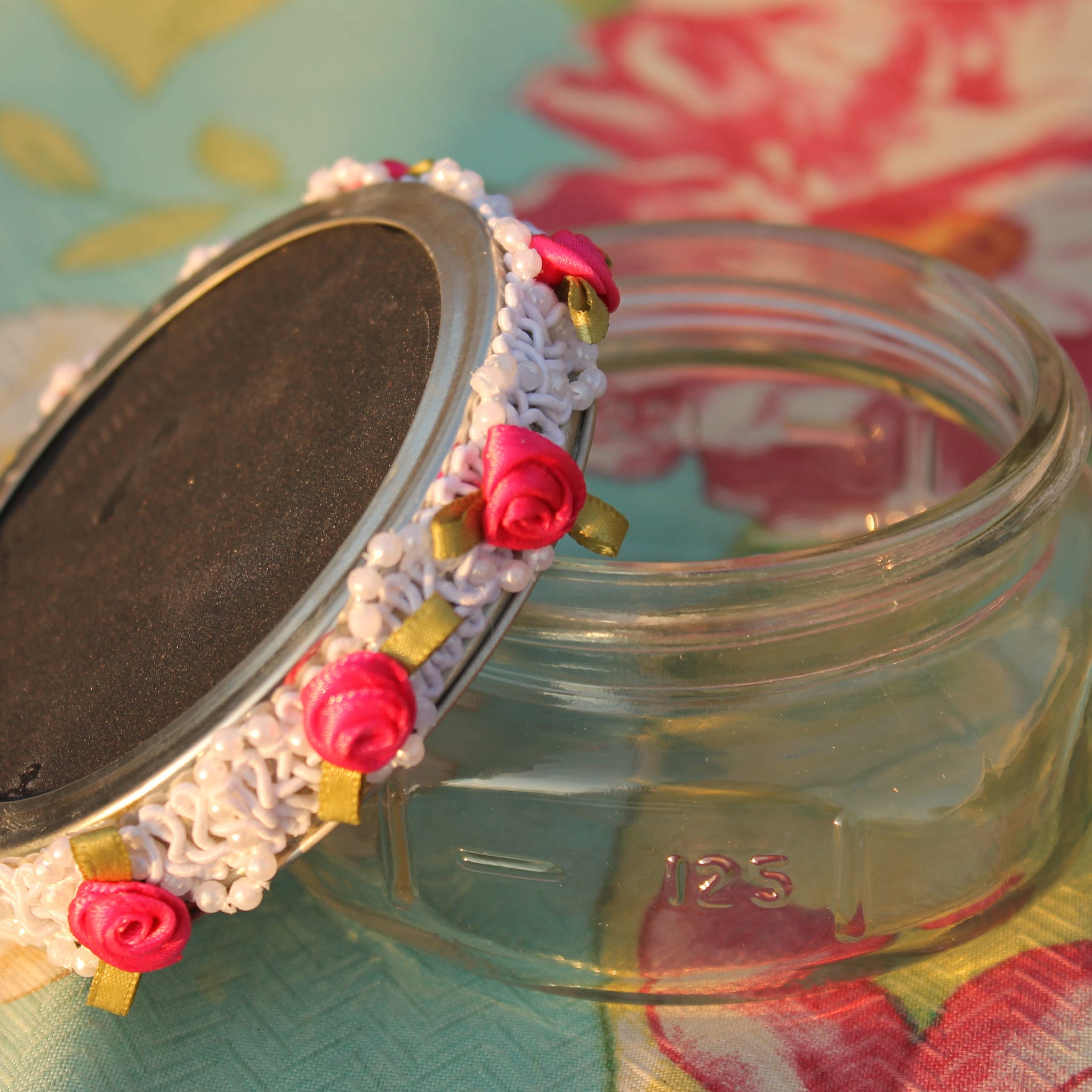 Glass jar with decorative lid, white beaded trim, pink ribbon roses, and clear glass body
