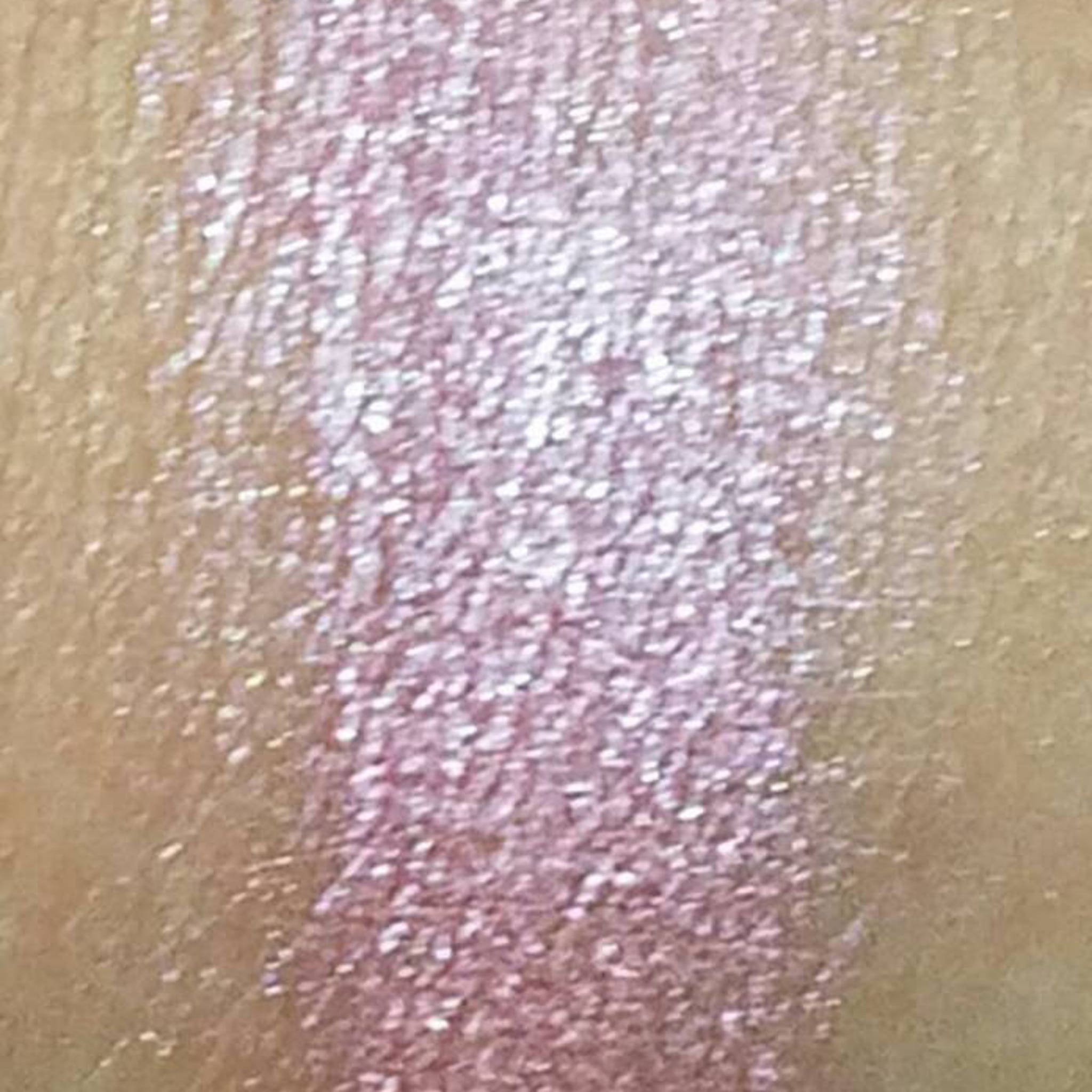 Side view of pink mineral eyeshadow in compact case showing pressed powder texture and shimmer finish