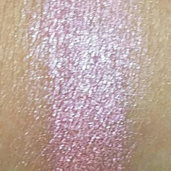 Side view of pink mineral eyeshadow in compact case showing pressed powder texture and shimmer finish