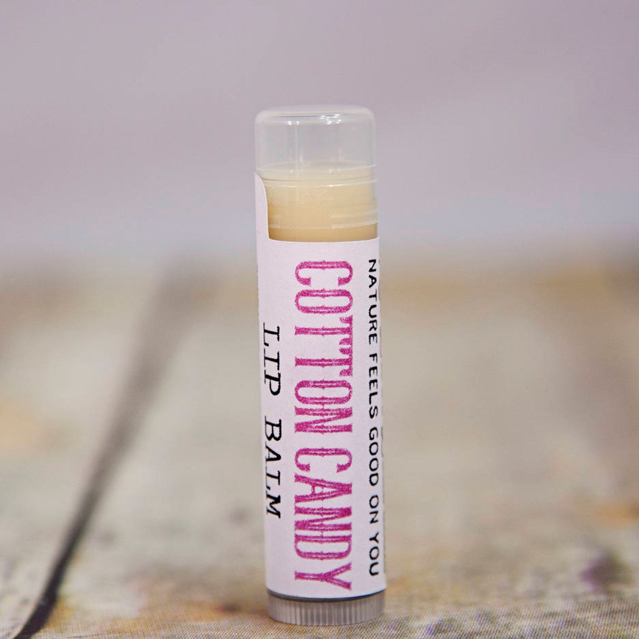 Lip balm tube with pink and white label, clear cap, and "Cotton Candy" text