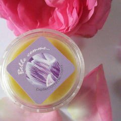 Lip balm in clear plastic container with Bellecomme label and pink rose petals around