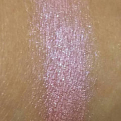 Woman applying soft pink mineral eyeshadow to eyelid with fingertip for a natural makeup look