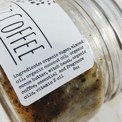 Coffee scrub in clear glass jar with white label, ingredients list visible