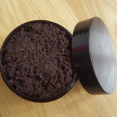 Brown granular material in black container with black lid on wooden surface
