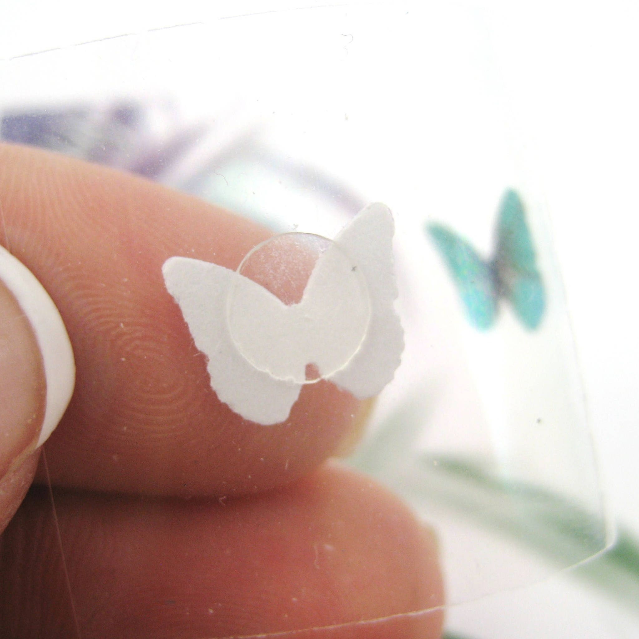 White glitter butterfly eyeshadow decals arranged on clear plastic packaging with silver detailing