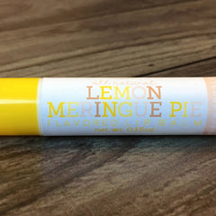 Lip balm tube with yellow and white, "Lemon Meringue Pie" text, on wood grain background