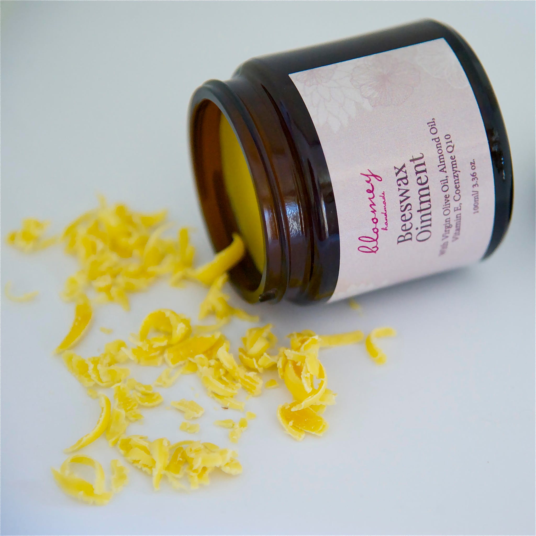 Beeswax ointment in a brown glass jar with yellow wax shavings and Bloomey label visible