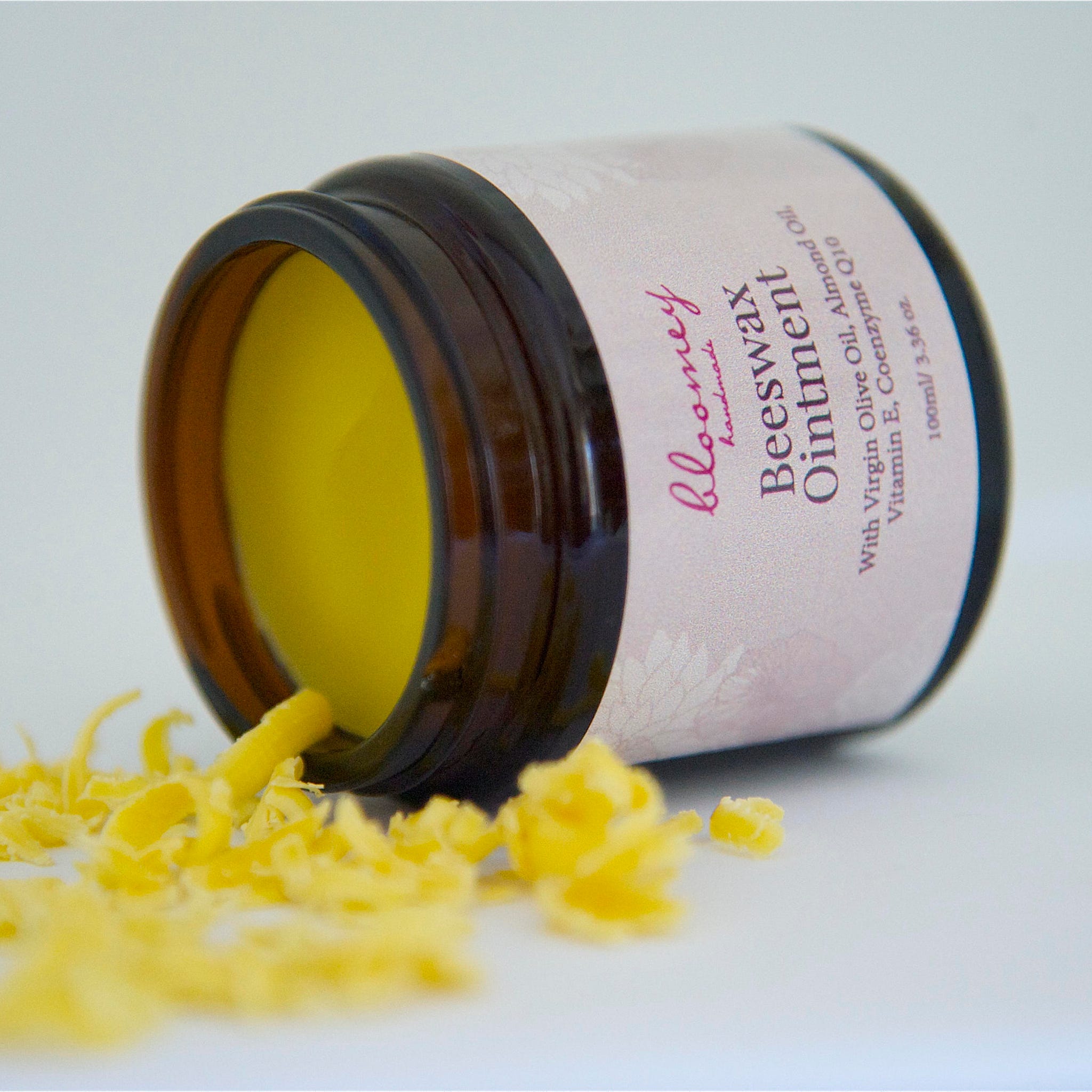 Beeswax ointment in a brown glass jar with yellow contents and shavings, Bloomey handmade label
