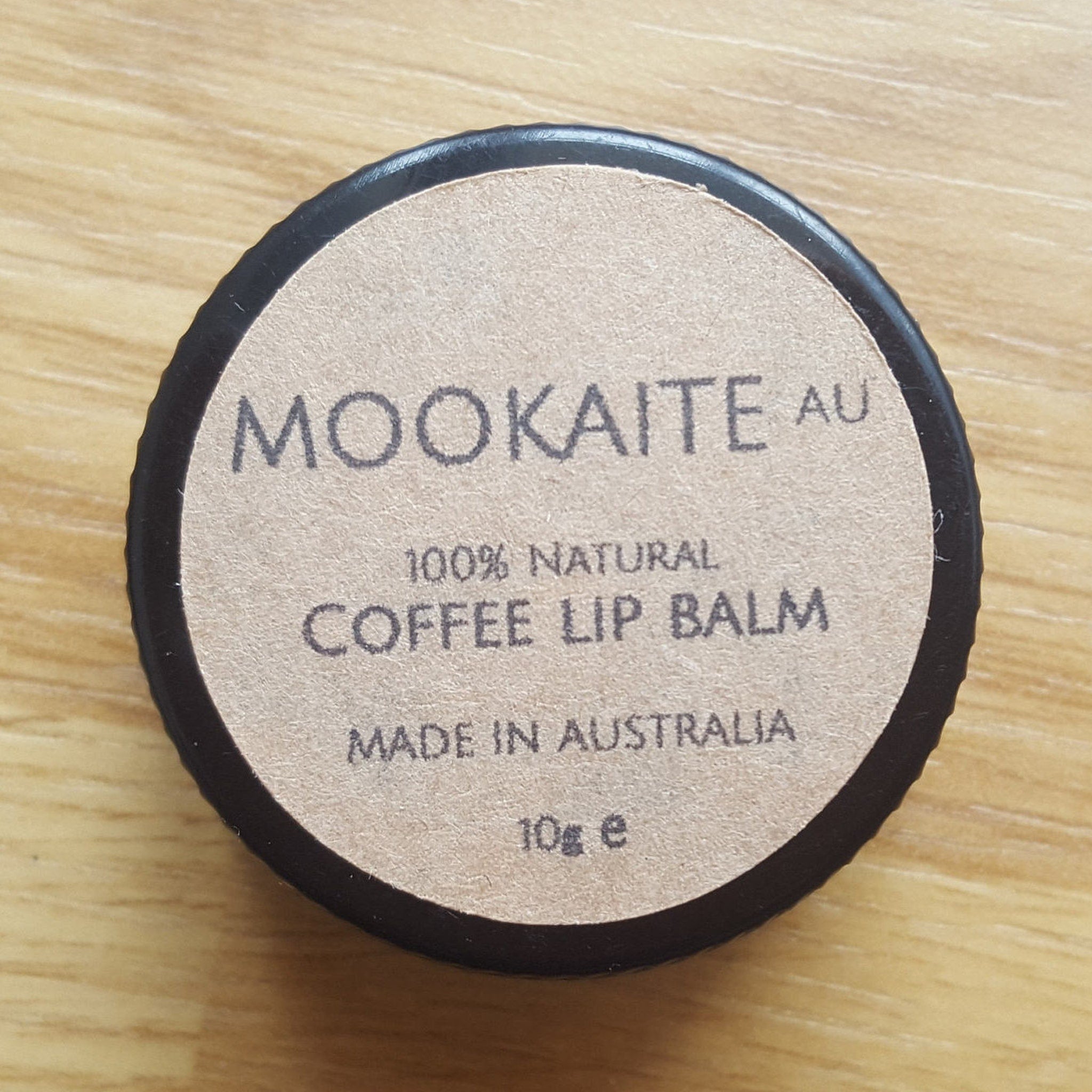 Coffee lip balm with brown paper label and black rim, "MOOKAITE AU" brand name visible