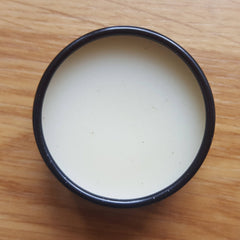 Creamy liquid in black rimmed bowl on wooden surface, top down view