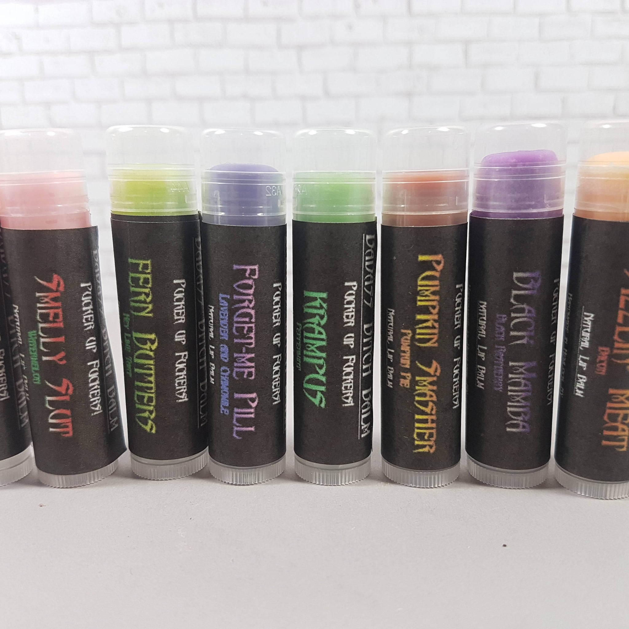 Lip balm tubes with various colors and labels, clear plastic lids, and black base