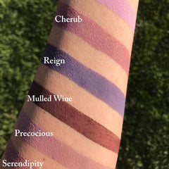 Close-up of vegan eyeshadow palette showing rich pigmented shades in matte and shimmer finishes with dual-ended brush