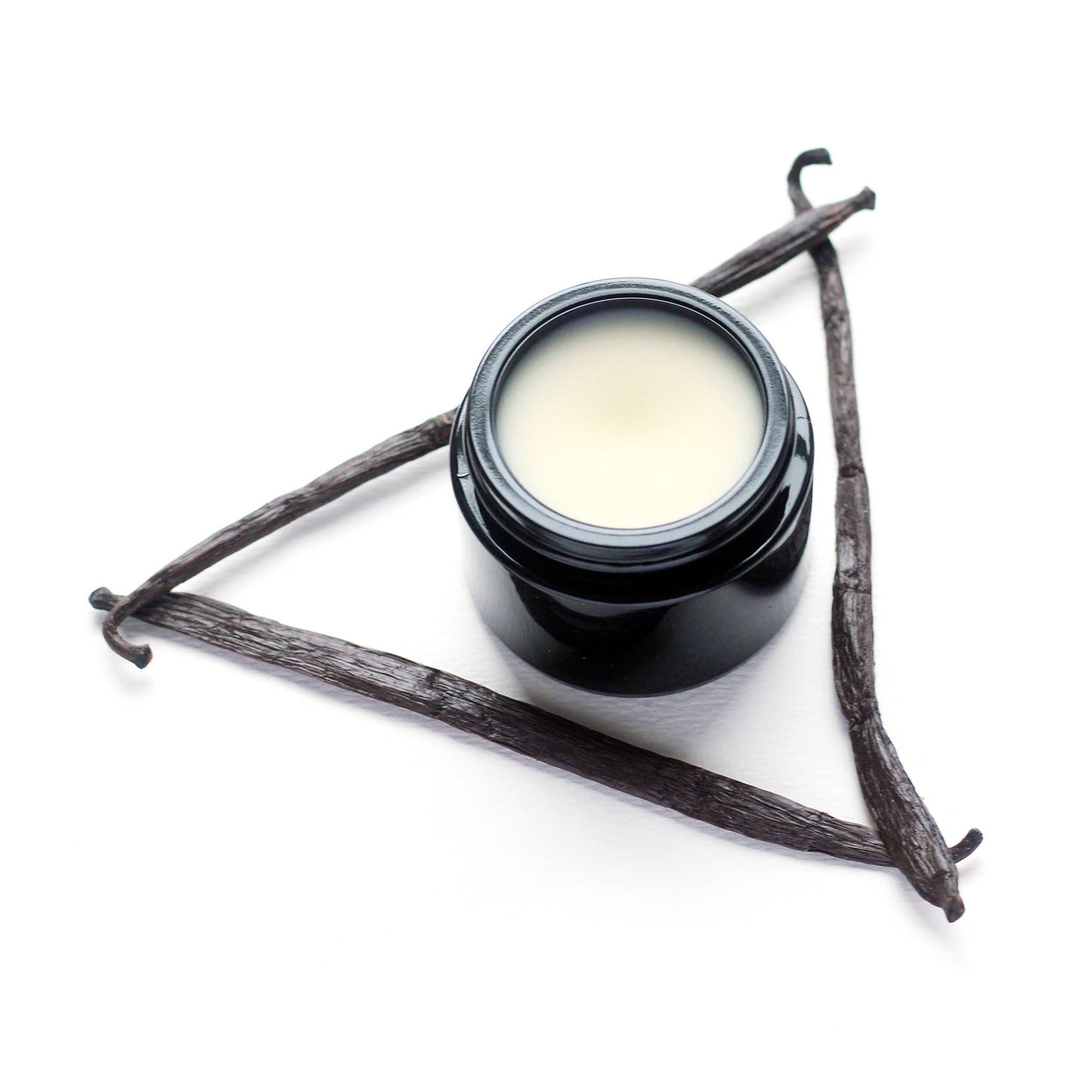 Close-up of golden vanilla moisturizer cream with silky texture in a sleek white jar