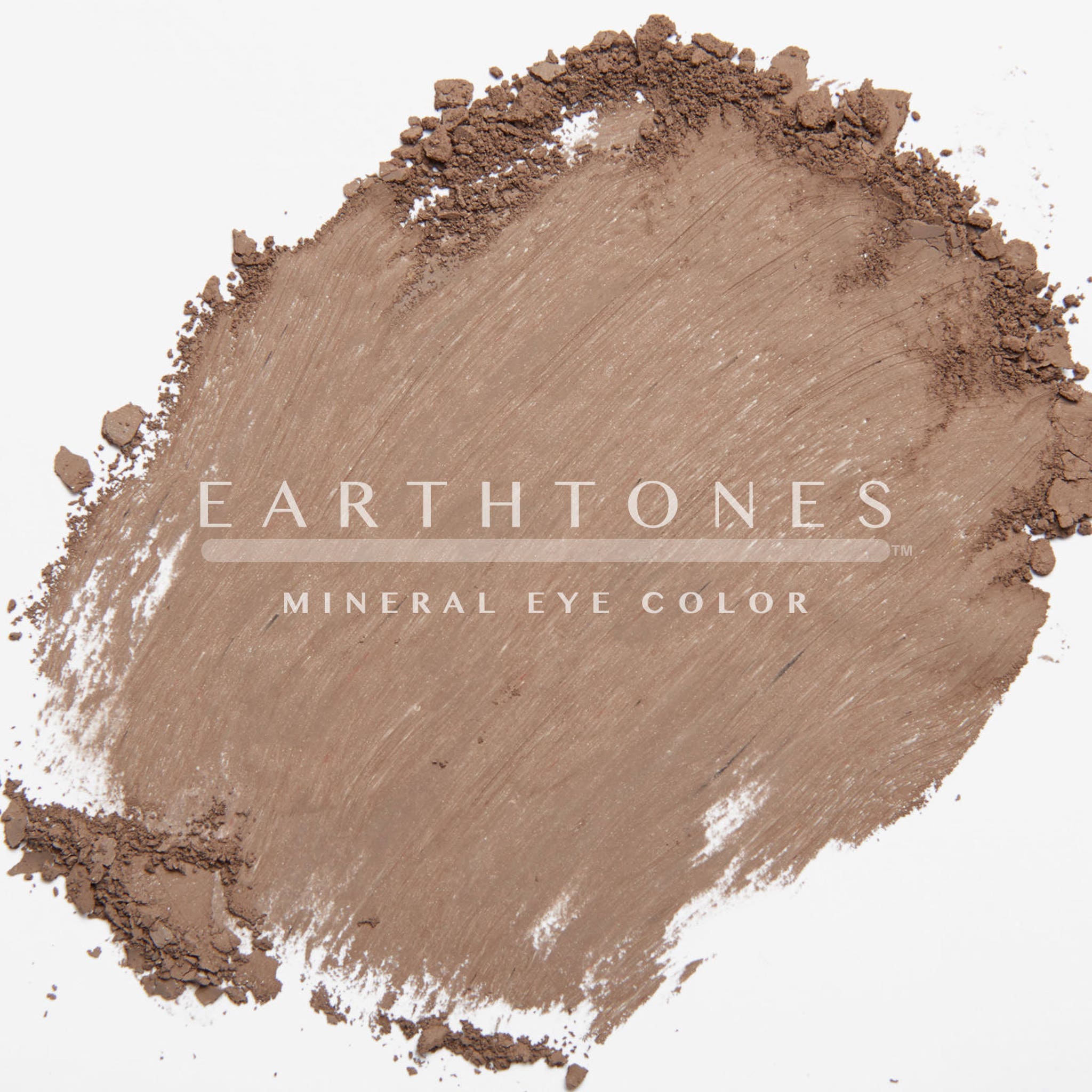Close-up of a makeup brush applying chocolate brown mineral eye shadow to eyelid, showcasing smooth pigmented blend