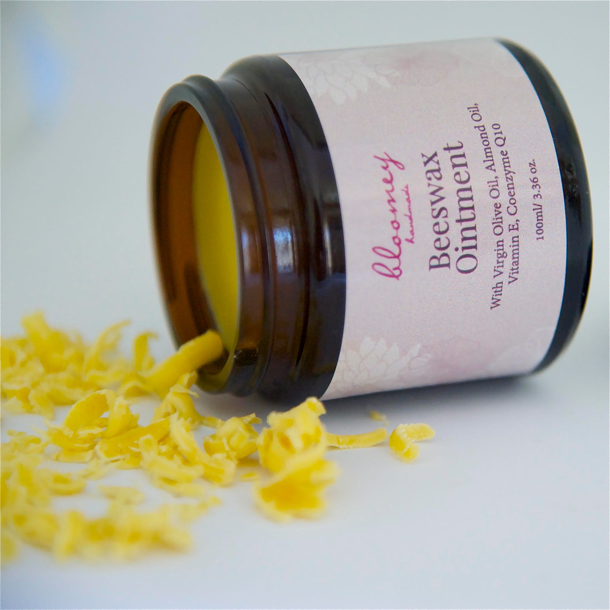 Beeswax ointment in brown glass jar with pink label, yellow contents, and "bloomey" text