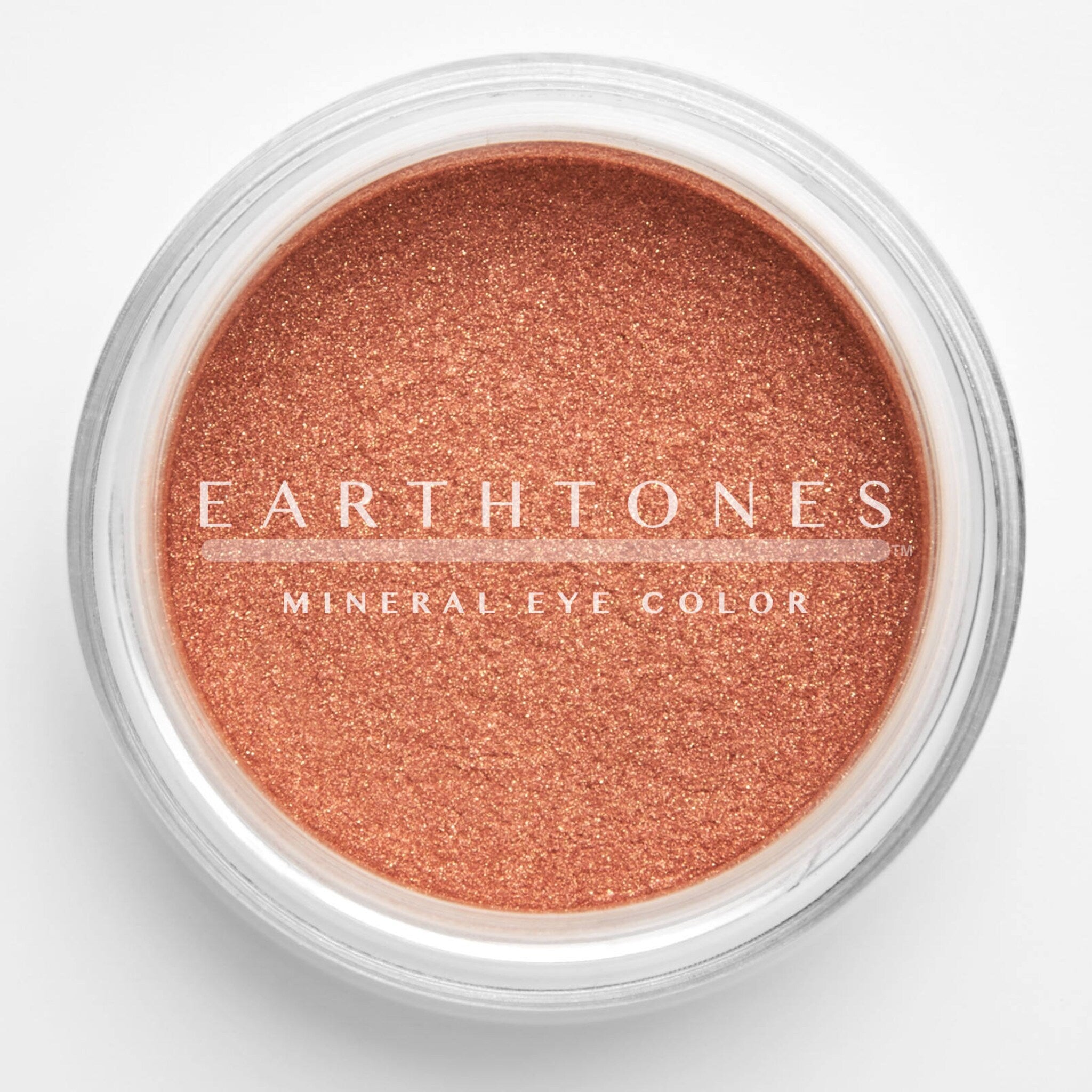 Close-up of warm copper mineral eye shadow with shimmering metallic finish in compact pan