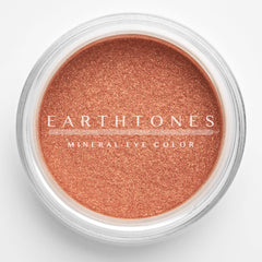 Close-up of warm copper mineral eye shadow with shimmering metallic finish in compact pan