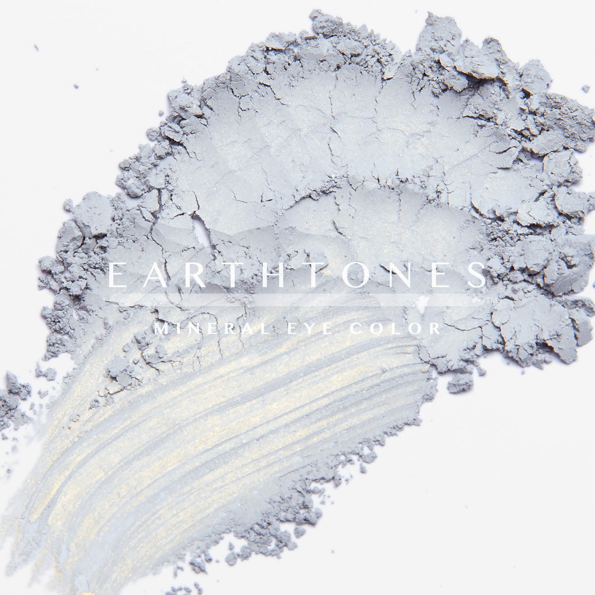 Close-up of a hand applying soft taupe mineral eye shadow with a fluffy brush for a blended look
