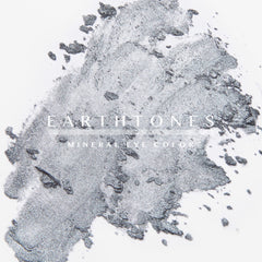 Woman applying shimmering silver mineral eye shadow to eyelid with fingertip for a metallic finish