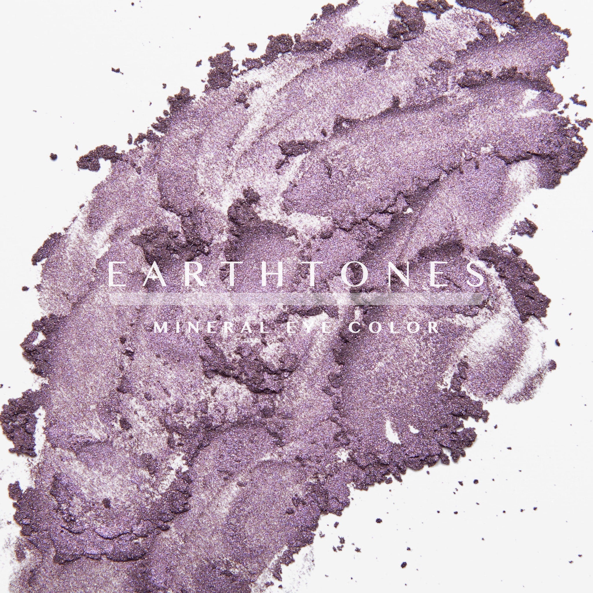 Woman applying plum mineral eyeshadow with a fluffy brush to eyelid, showcasing rich purple pigment blend