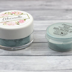 Side angle of frosty aqua blue mineral eyeshadow pan with shimmer finish, showcasing texture depth