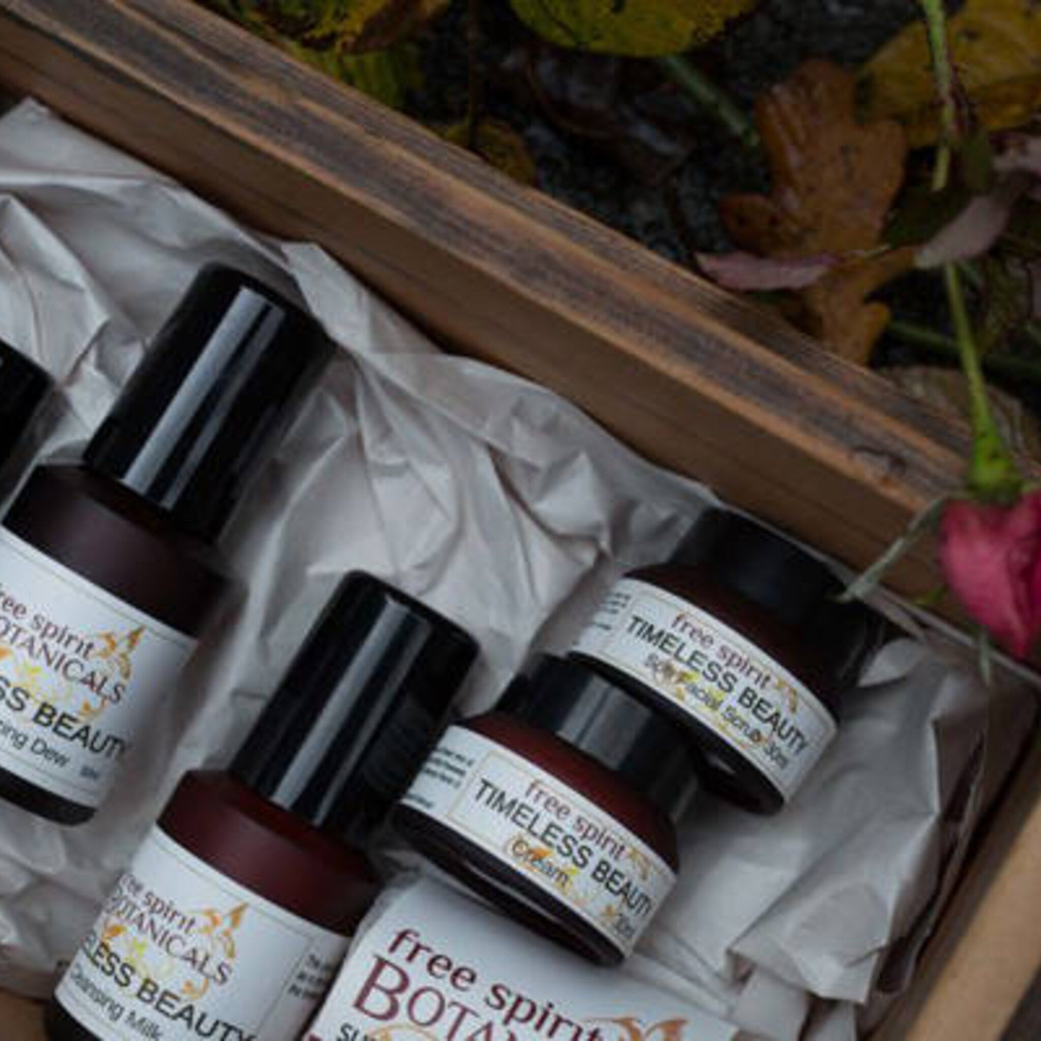 Skincare products in brown glass bottles with black lids, in a wooden box with white paper, Free Spirit Botanicals brand visible