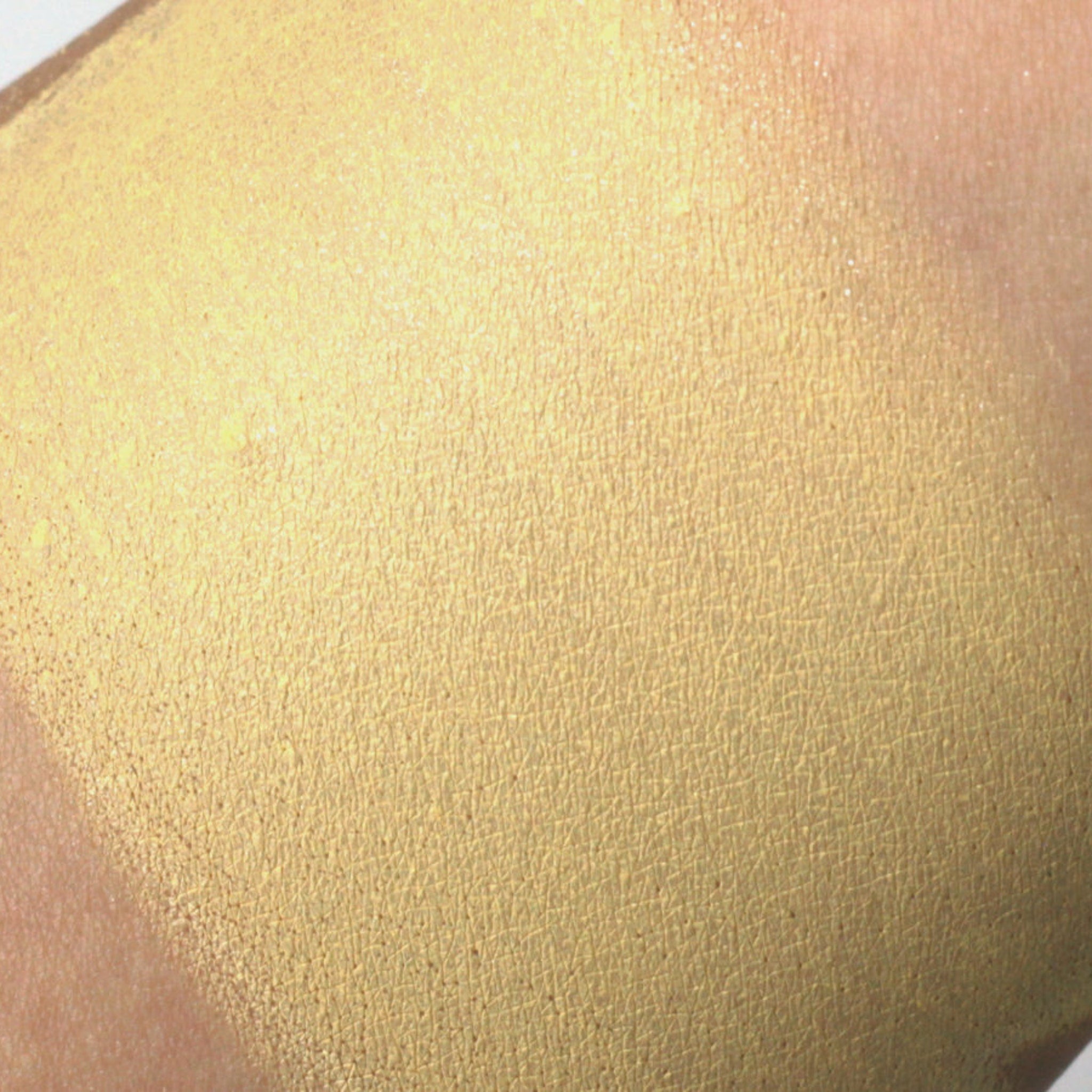 Close-up of shimmery pale yellow vegan mineral eyeshadow with soft buttery texture in compact pan