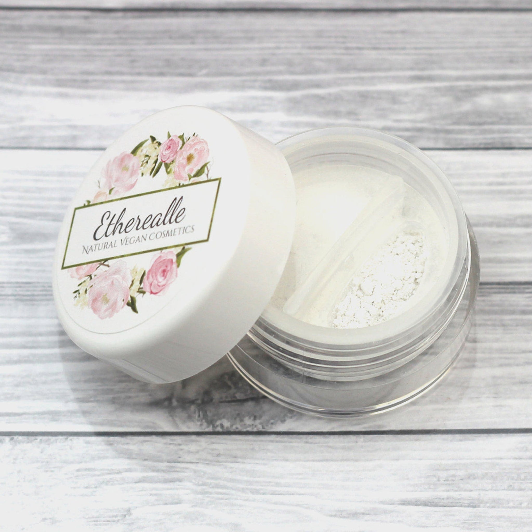 Small plastic sample jar of shimmery white mineral eyeshadow with silver lid on marble surface