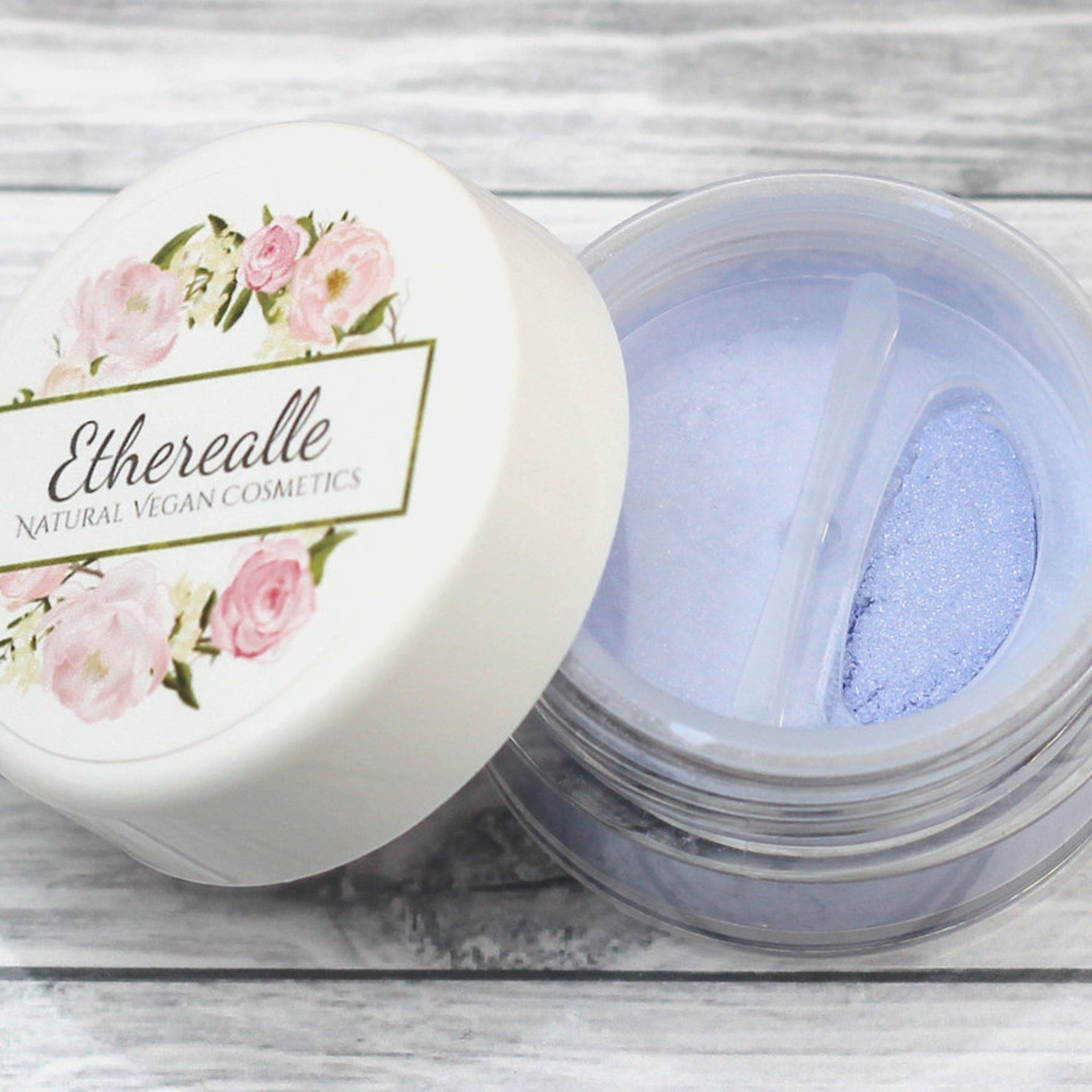 Eyeshadow powder with light blue shimmer, clear jar, and Etherealle branding on lid