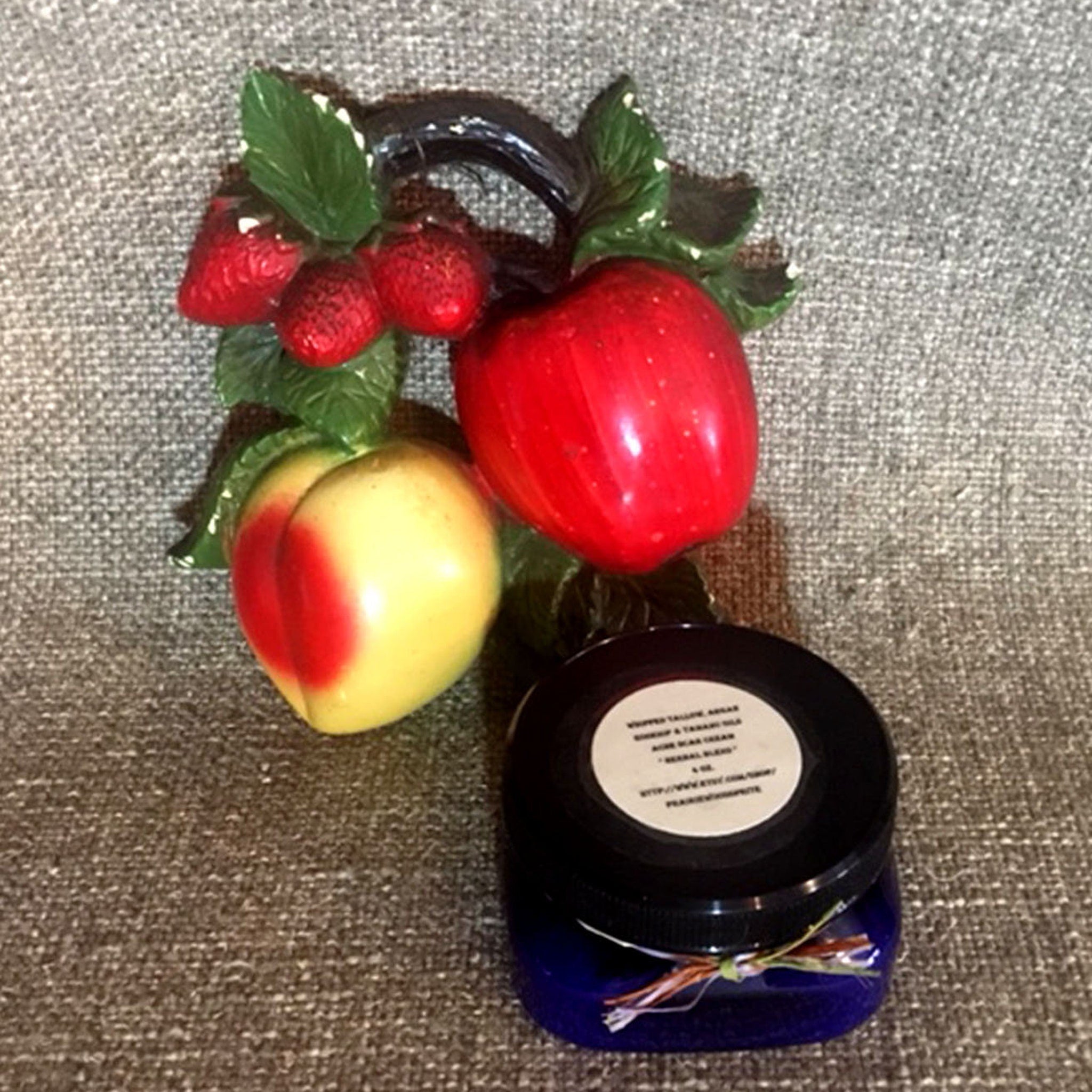 Fruit decor with red, yellow, and green colors, and a blue jar with a white label, on a textured surface