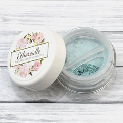 Close-up of shimmering frosty aqua blue eyeshadow being applied with a brush for a bold, metallic eyelid look.