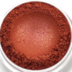 Eyeshadow powder in reddish-brown color with glitter particles and a powdery texture in a clear container