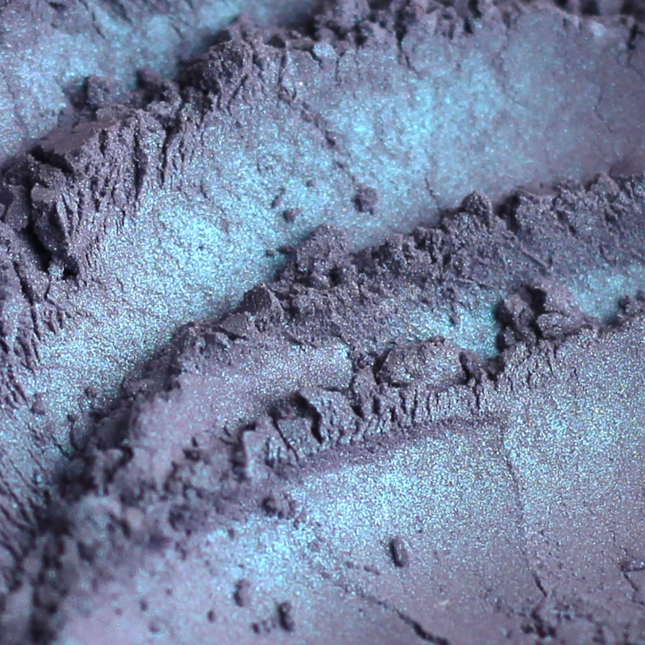 Iridescent powder with blue and purple hues, textured surface, for eyeshadow application