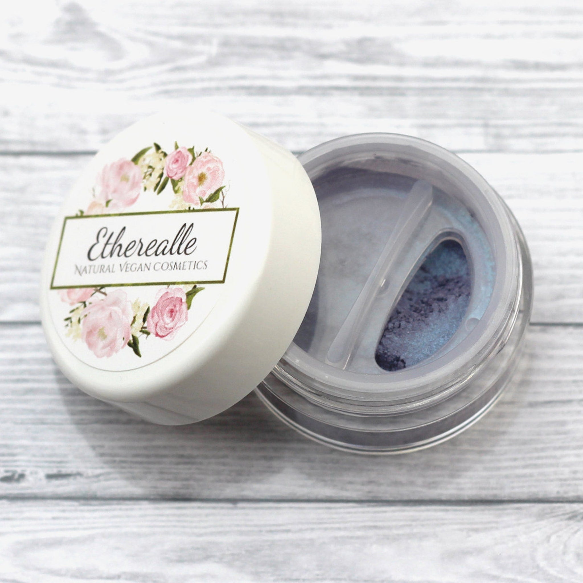 Etherealle powder cosmetic jar with white lid, floral design, and blue powder inside