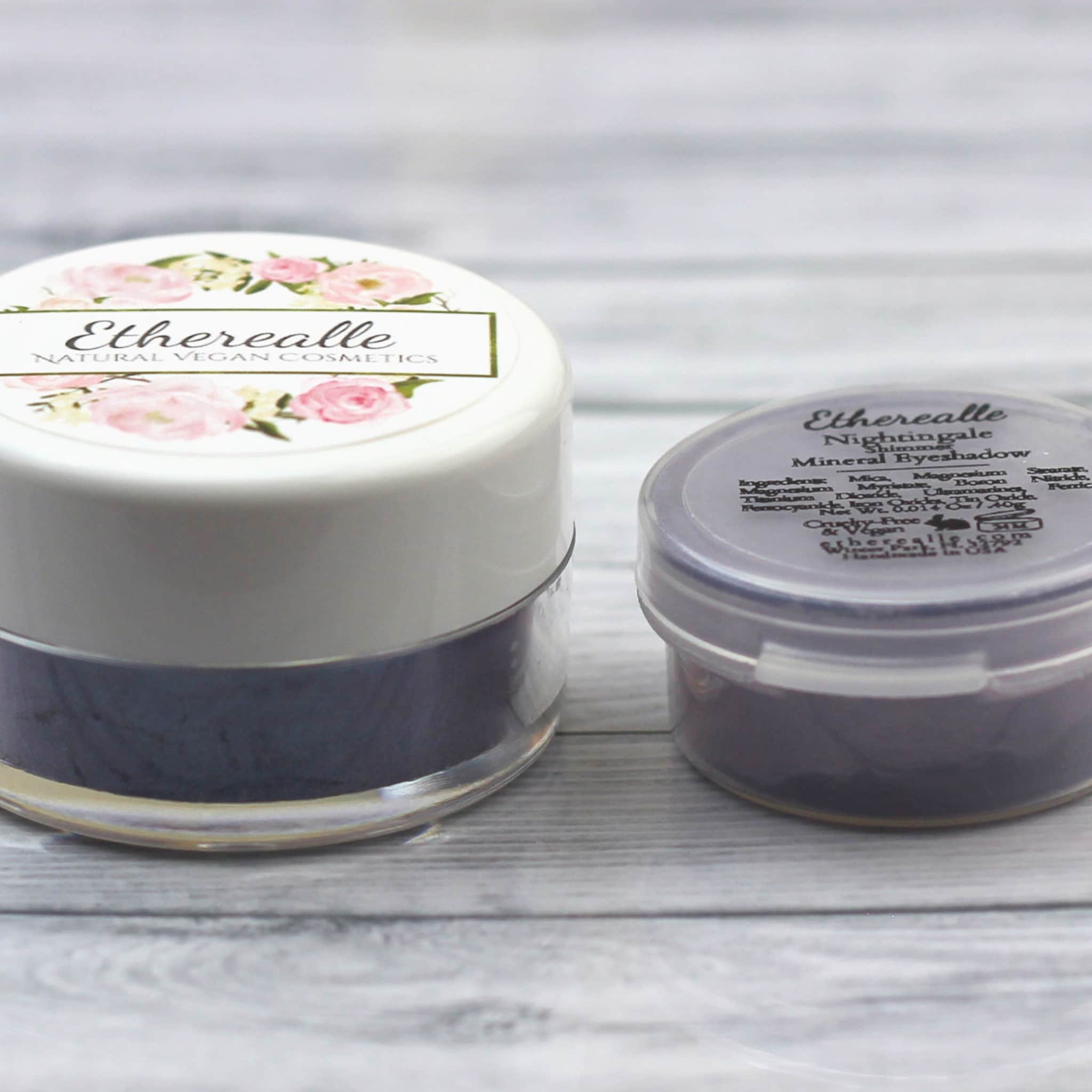 Eyeshadow pots with white and purple lids, dark purple powder, and Etherealle label visible