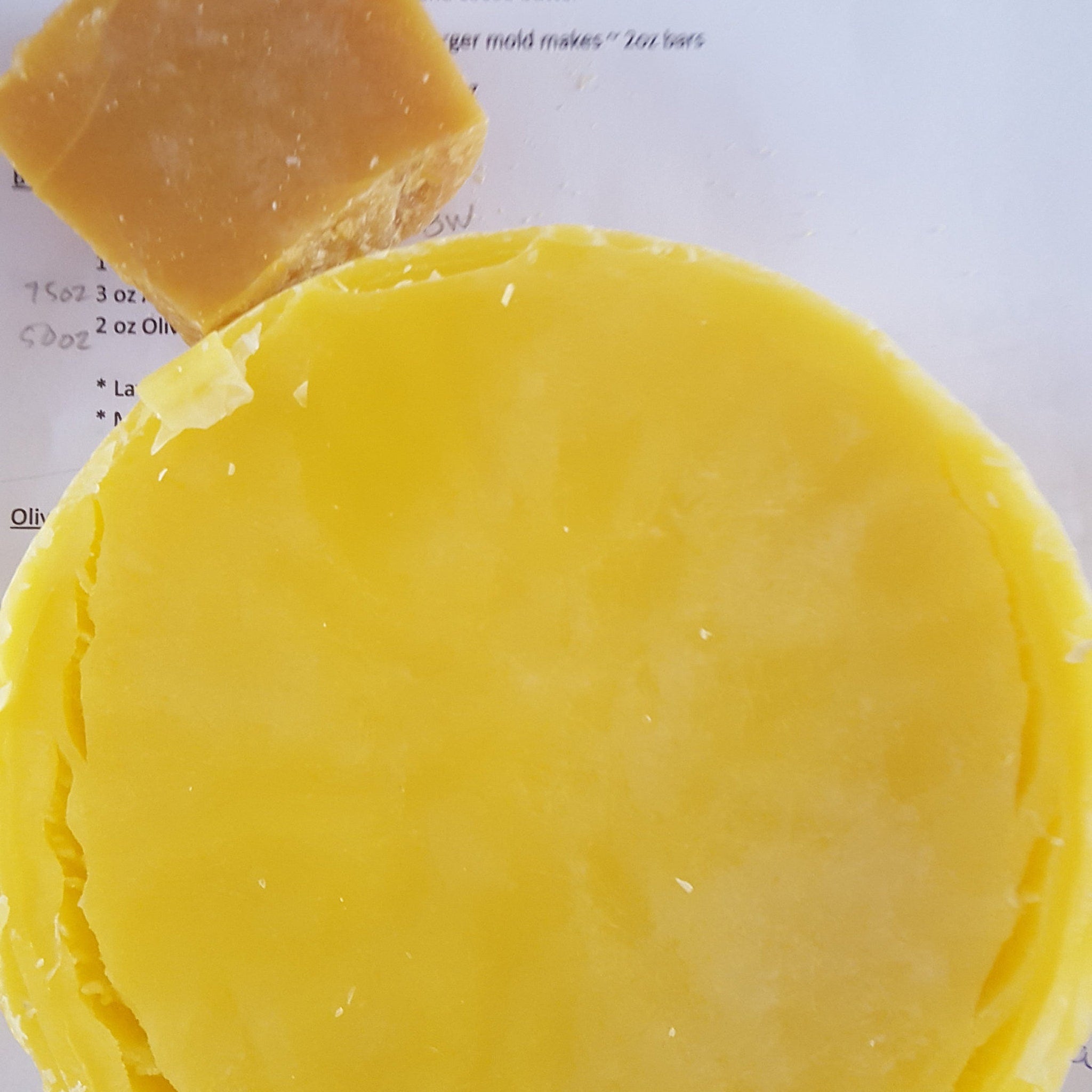 Yellow wax block with rough edges and smooth surface, sitting on paper with text