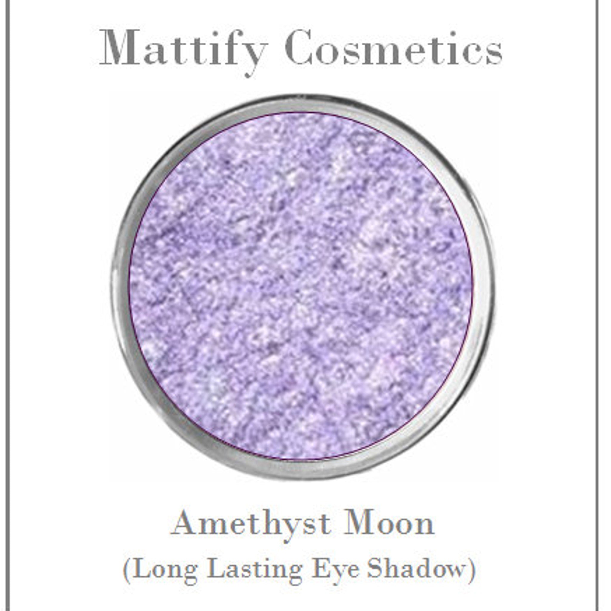 Close-up of sparkly black and teal eyeshadows with matte blue in vegan mermaid palette, showing texture detail