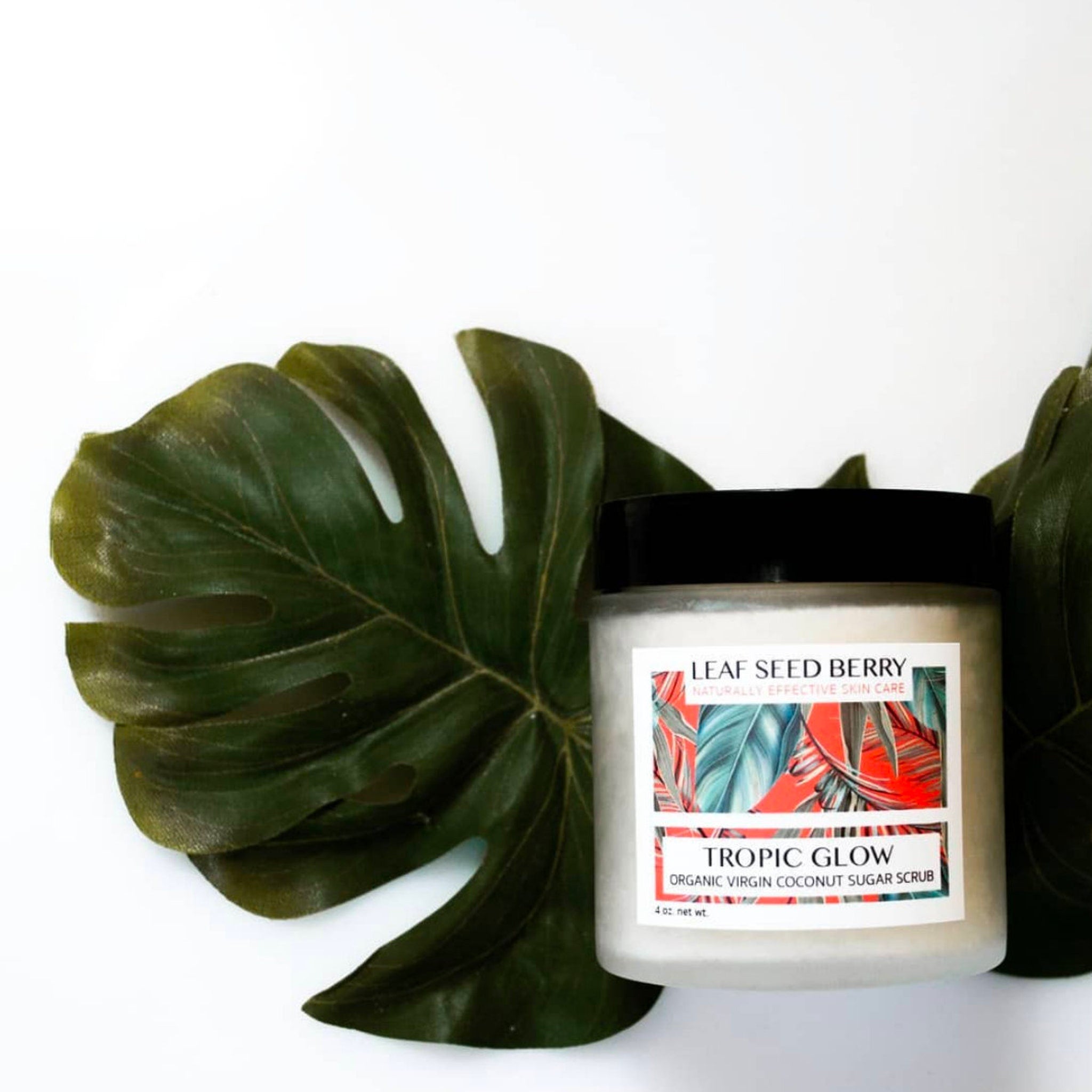 Sugar scrub jar with black lid, white label, and green leaf background