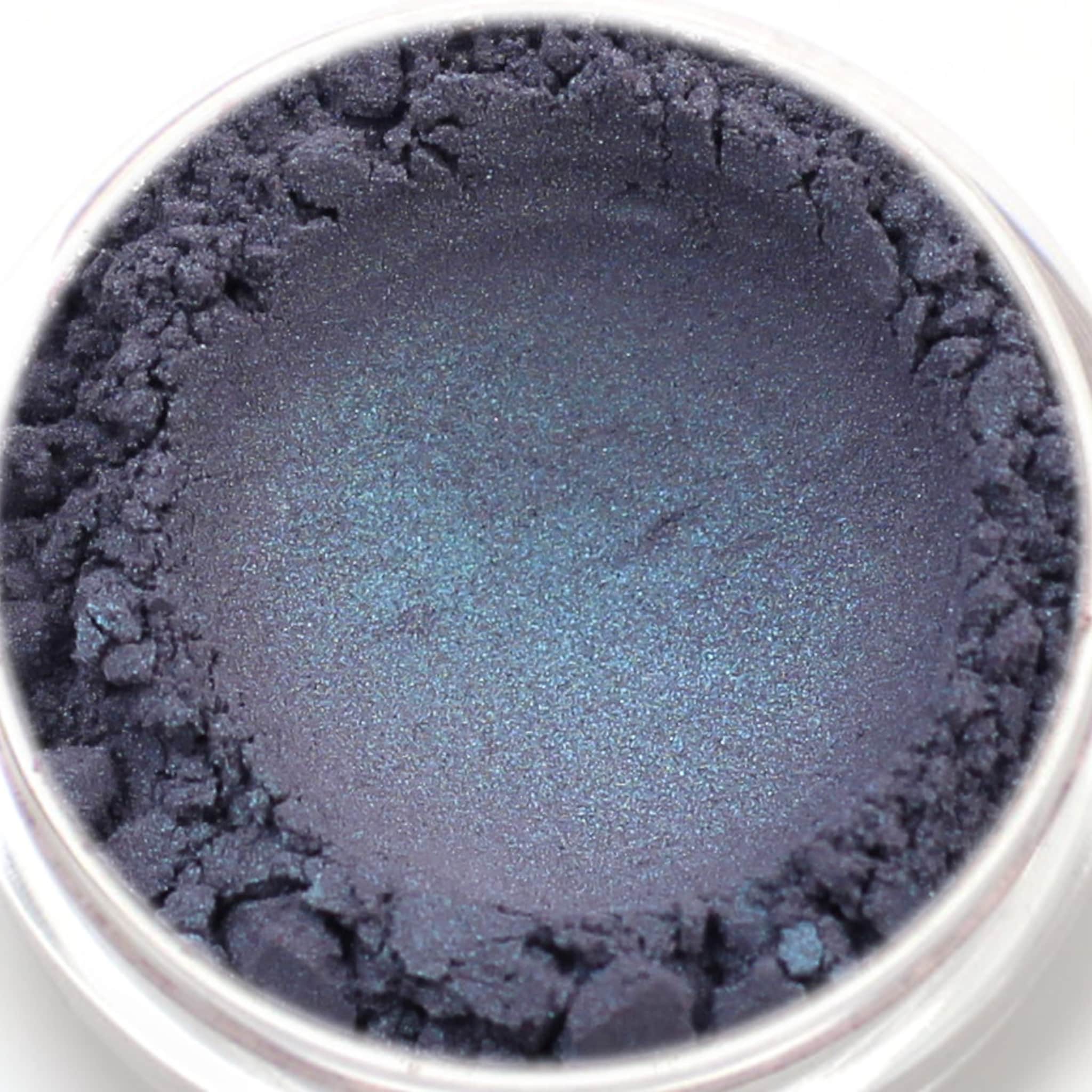 Eyeshadow powder in dark blue with shimmer and textured surface in a clear container