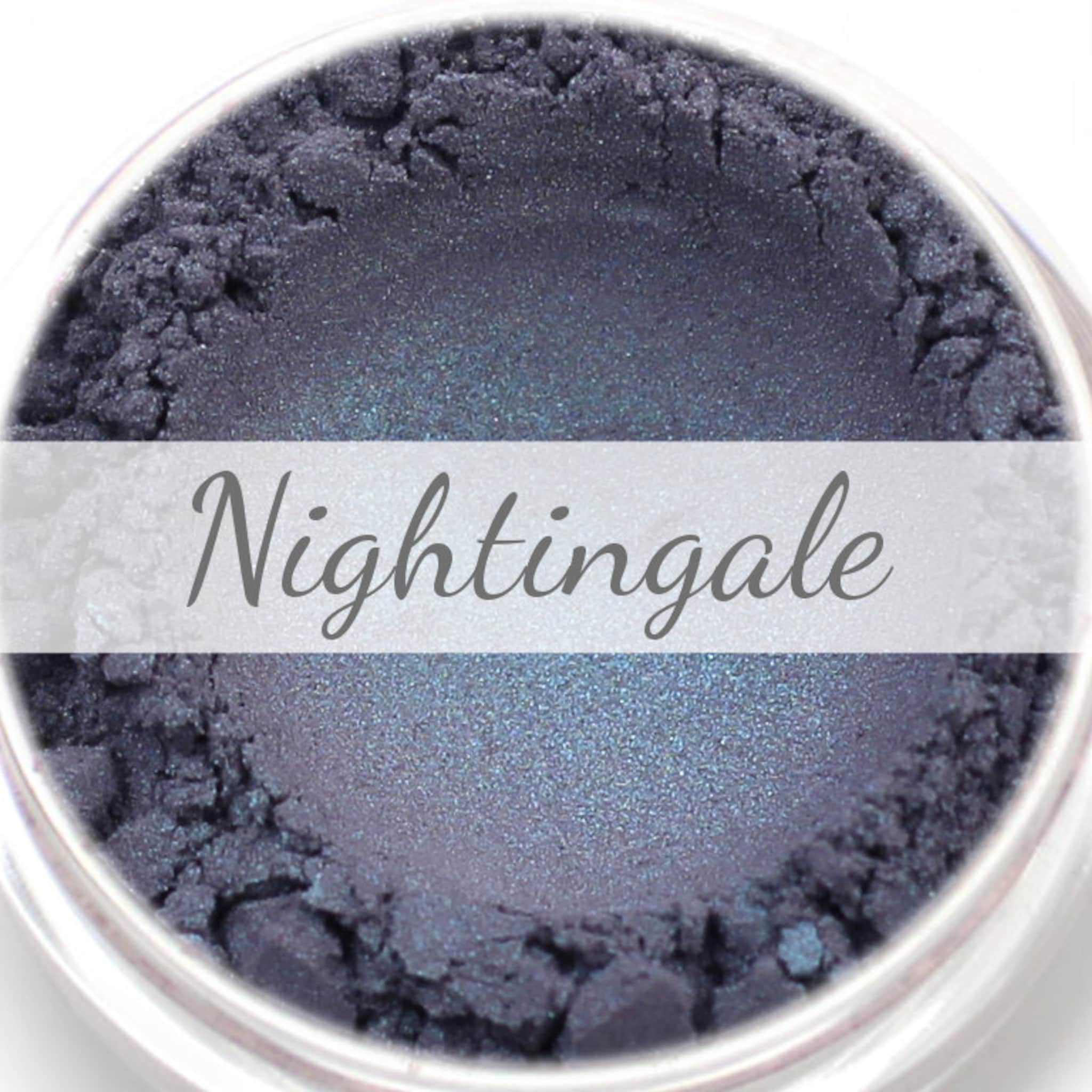 Eyeshadow powder with indigo and turquoise duochrome color, "Nightingale" text visible